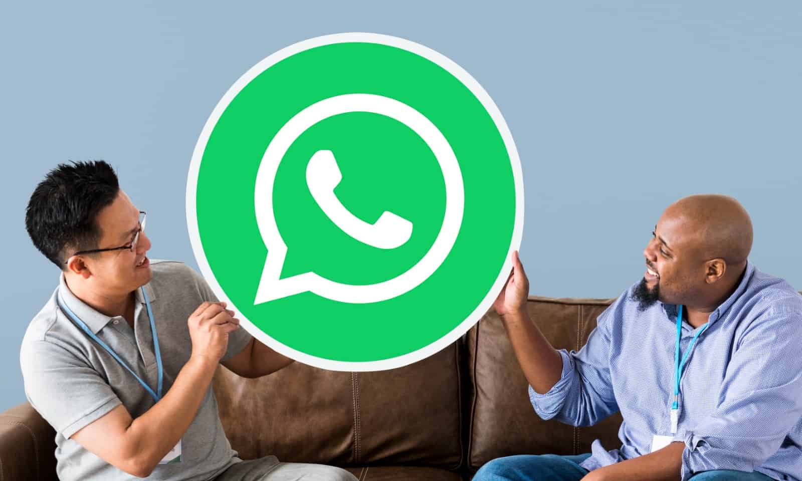 Duas pessoas segurando um grande ícone do WhatsApp.