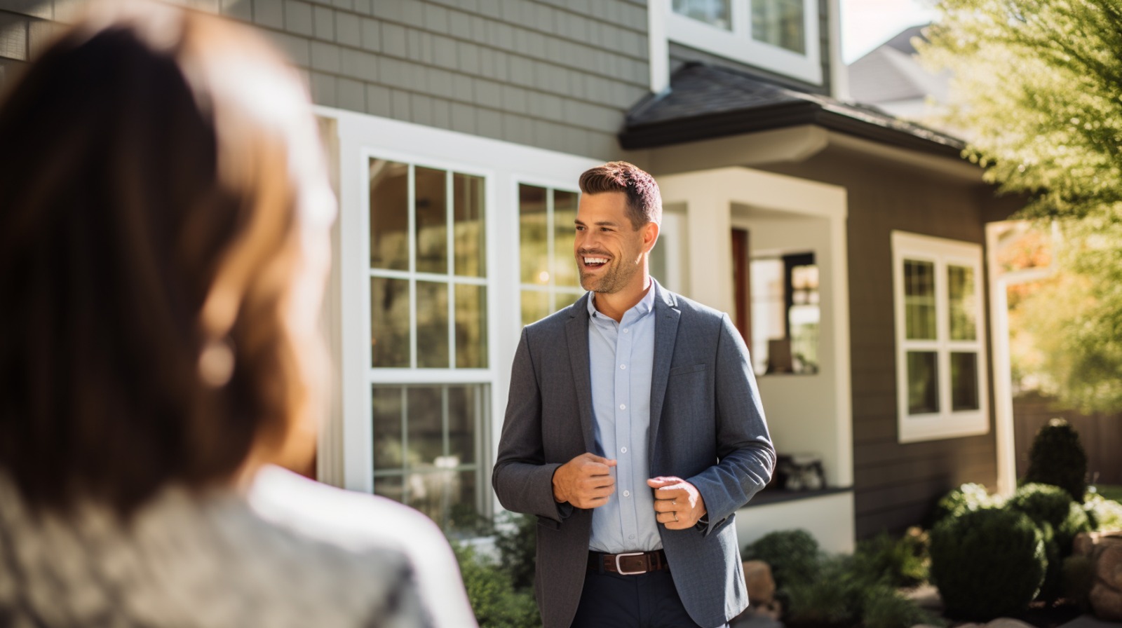 Homem de terno em frente a uma casa moderna interagindo com outra pessoa, representando o trabalho de profissionais do ramo imobiliário que possuem CRECI.