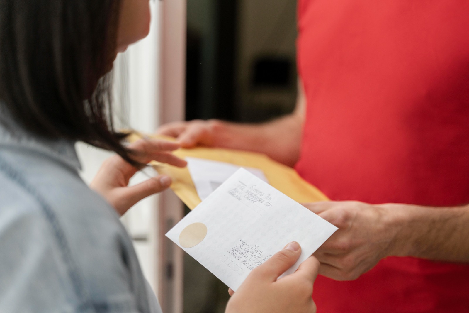 Uma pessoa recebendo um envelope amarelo e um papel com informações escritas, possivelmente relacionadas à Anuidade do creci.